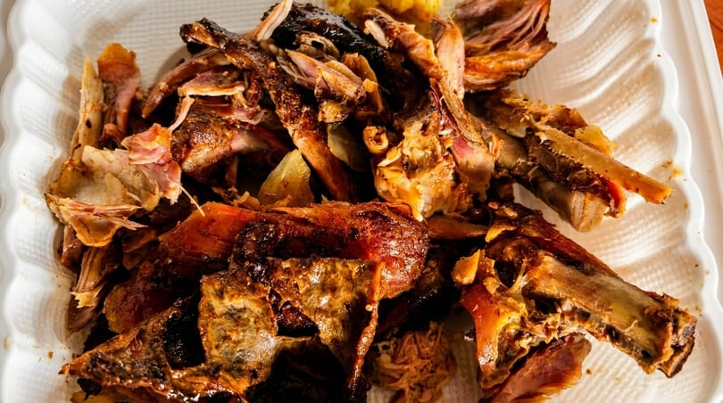 Close-up of a pile of cooked, shredded meat and bones on a white plate.